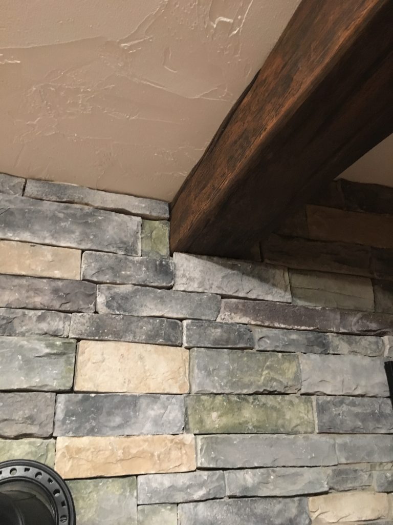 Close-up view of Timber beams slotted into the living room's new stone wall.