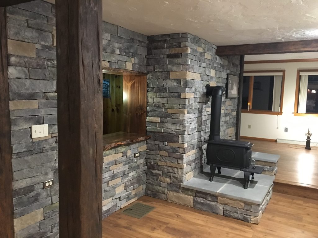 Open layout room in an Oxford, PA home transformed with Custom Timber beams, new stone walls and a Franklin stove.