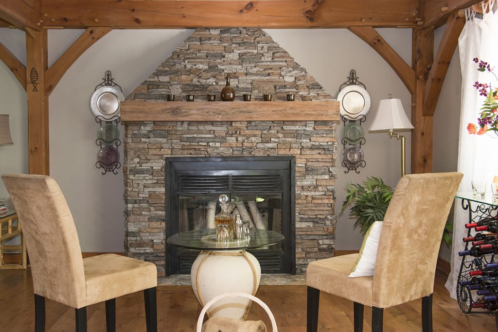 Living room in NH home blending a faux wood mantel with real wood beams.