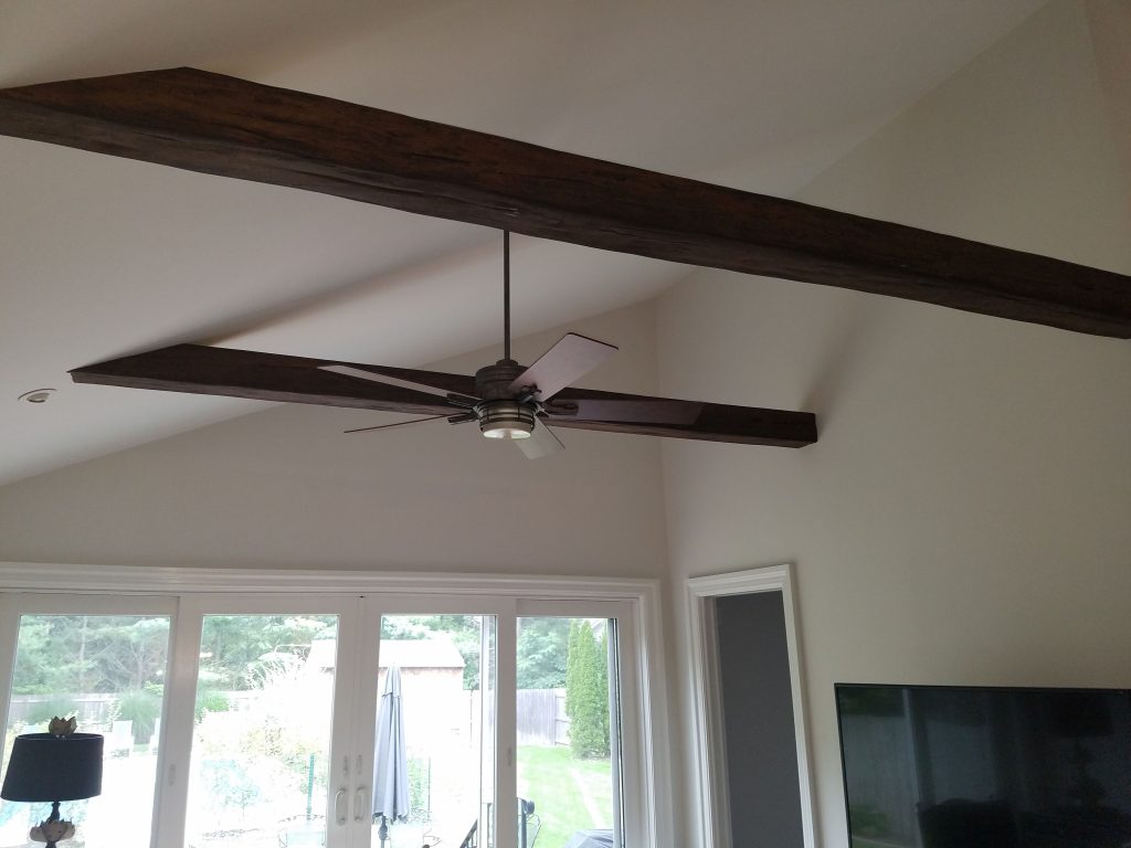 The look of real exposed rafters created in a living room using faux beams.