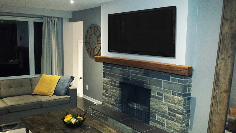 8 foot long faux mantel installed over a living room's real stone fireplace.