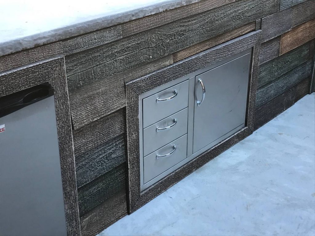 Drawers and cabinets on an outdoor kitchen framed with barn board style planks