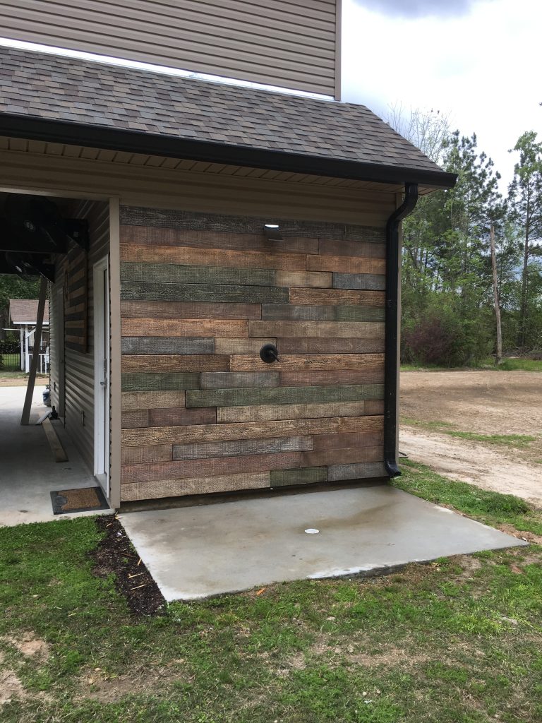 DIY outdoor shower wall created with waterproof, barn board style panels that mimic real reclaimed wood.