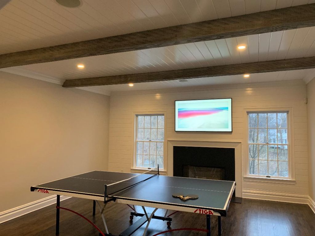 Living room updated with faux salvaged beams installed over a white plank ceiling.