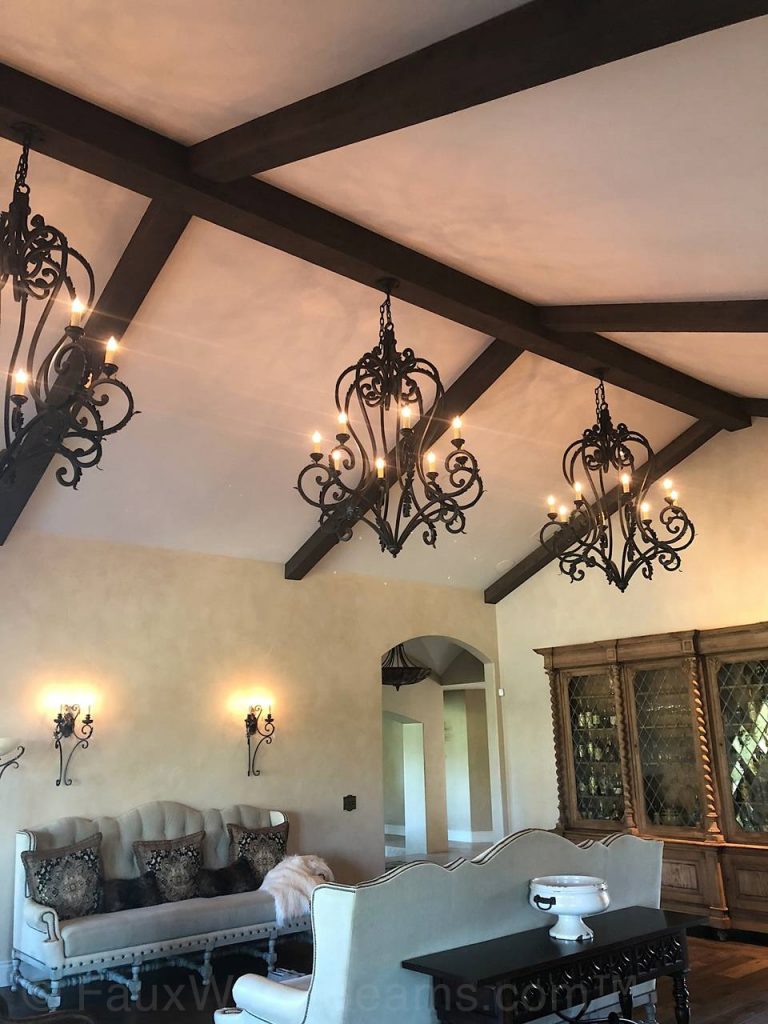 Hollow faux beams conceal chandelier wiring and mounts.