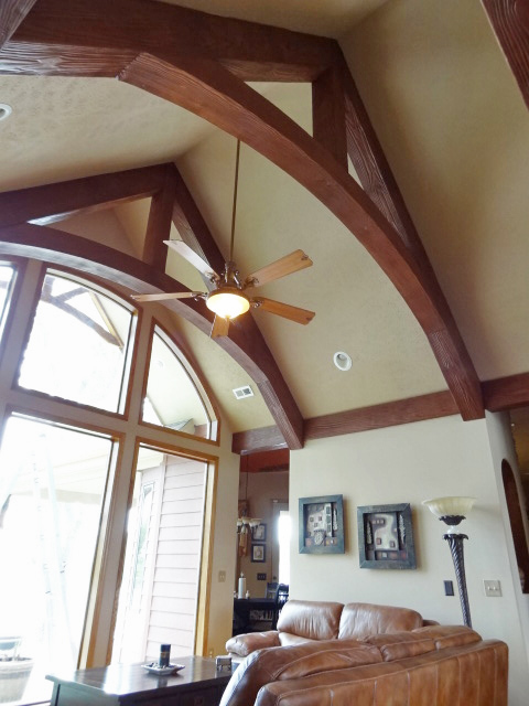 An Arched King Truss built with Woodland beams overlooks a cozy living room.
