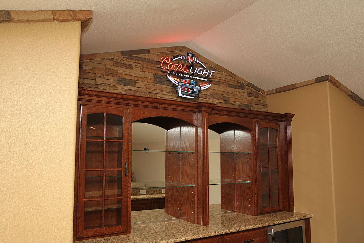 Faux stone panels creating a rustic wall for a football fan home bar design